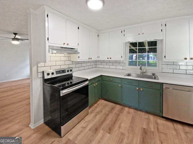 kitchen with ceiling fan, sink, green cabinetry, stainless steel appliances, and light hardwood / wood-style floors