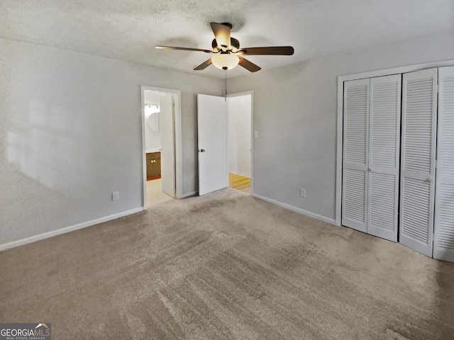 unfurnished bedroom featuring ceiling fan, light colored carpet, a closet, and connected bathroom