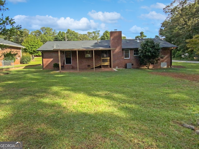 rear view of property with central AC unit and a yard