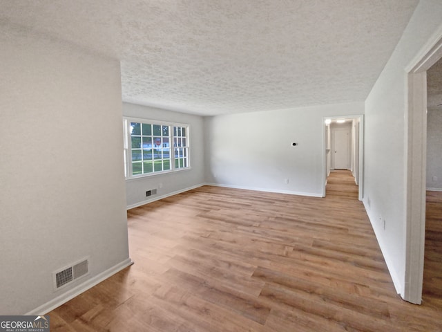 unfurnished room featuring a textured ceiling and light hardwood / wood-style floors