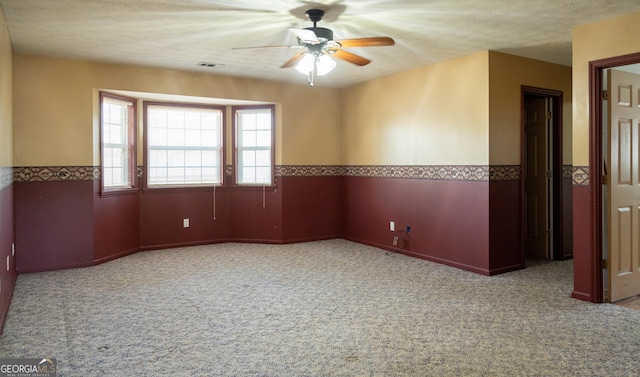 unfurnished room with a textured ceiling, light colored carpet, and ceiling fan