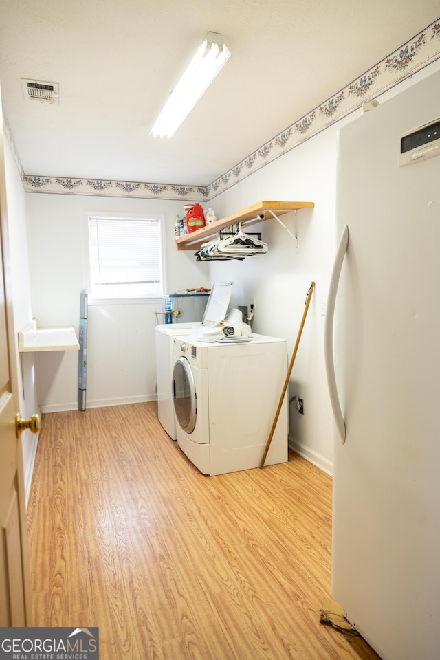 laundry room with hardwood / wood-style flooring and washing machine and dryer