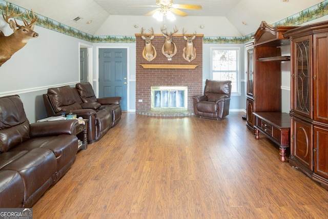 living room featuring hardwood / wood-style flooring, vaulted ceiling, ceiling fan, and a fireplace