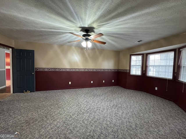 empty room with ceiling fan, carpet floors, and a textured ceiling