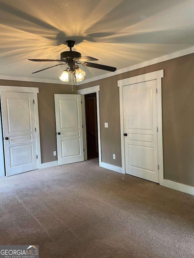 unfurnished bedroom with carpet, ornamental molding, and ceiling fan