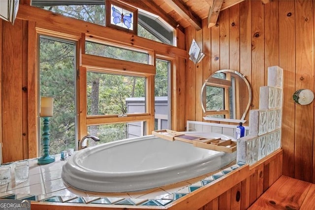 bathroom featuring wooden walls, a bathtub, lofted ceiling with beams, and wooden ceiling