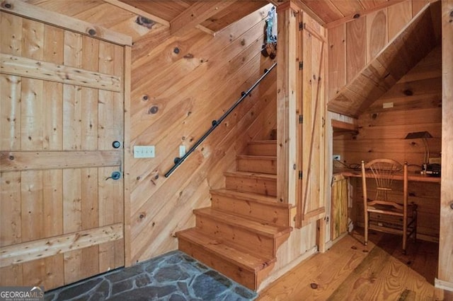 stairway featuring wood-type flooring, wood walls, vaulted ceiling, and wooden ceiling