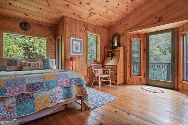 bedroom featuring multiple windows, wood walls, wood ceiling, and light wood-type flooring