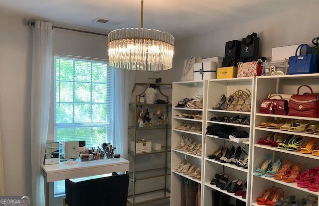 walk in closet featuring a notable chandelier