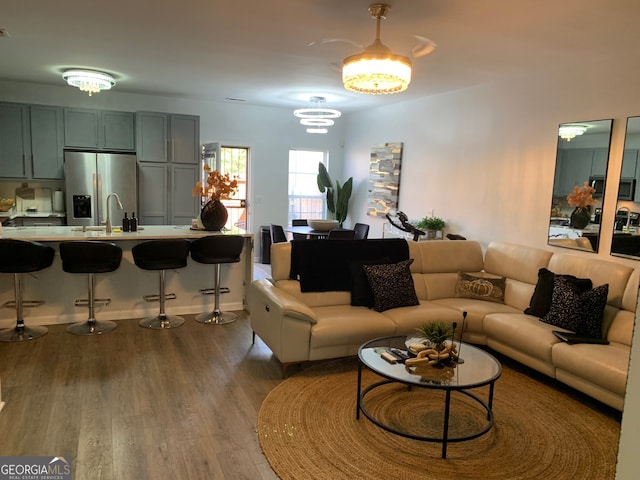 living room featuring wood-type flooring, sink, and a chandelier