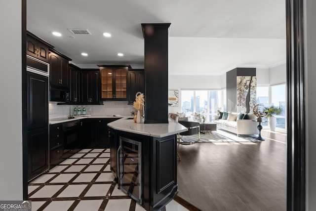 kitchen with a kitchen breakfast bar, a kitchen island, black appliances, beverage cooler, and dark brown cabinetry