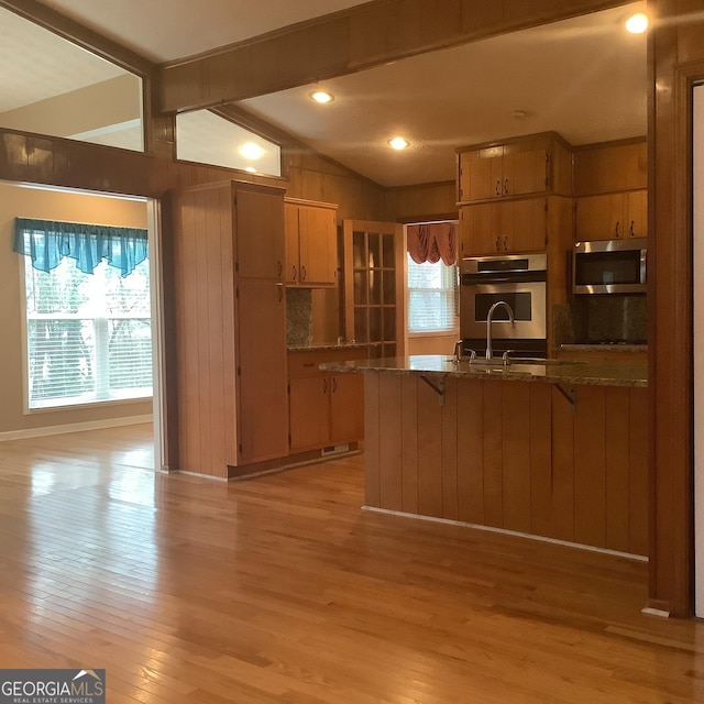 kitchen featuring stainless steel microwave, lofted ceiling with beams, plenty of natural light, and light wood-style floors