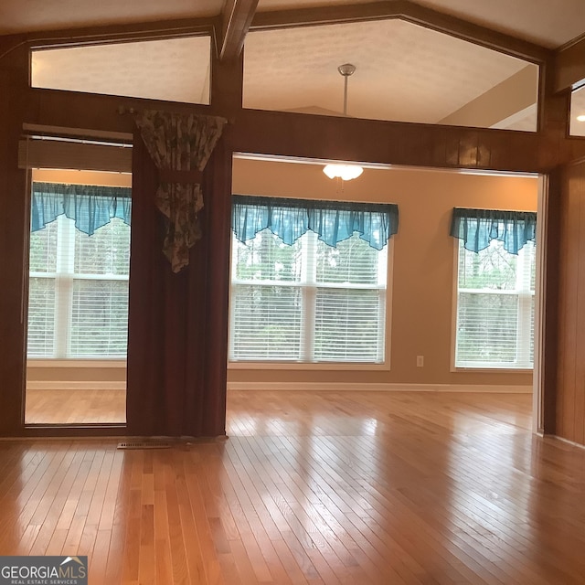 interior space with wood-type flooring and vaulted ceiling with beams