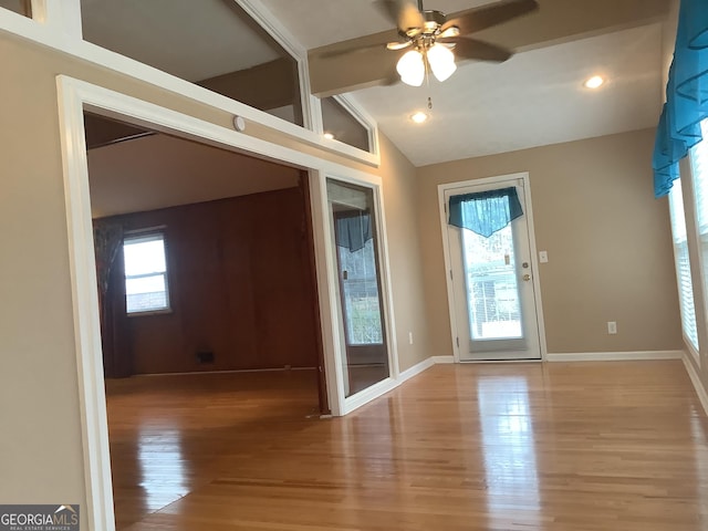 interior space featuring baseboards, plenty of natural light, wood finished floors, and vaulted ceiling with beams