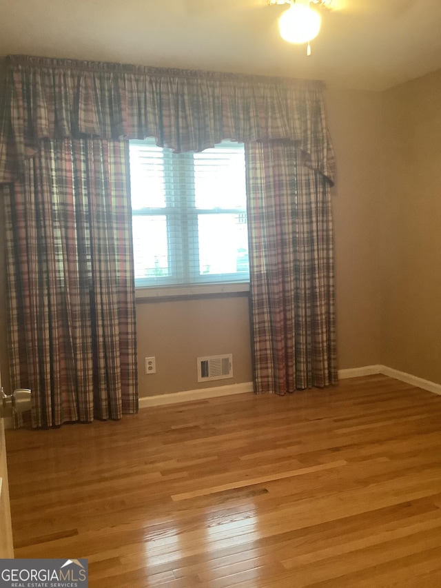 empty room featuring visible vents, baseboards, and wood finished floors