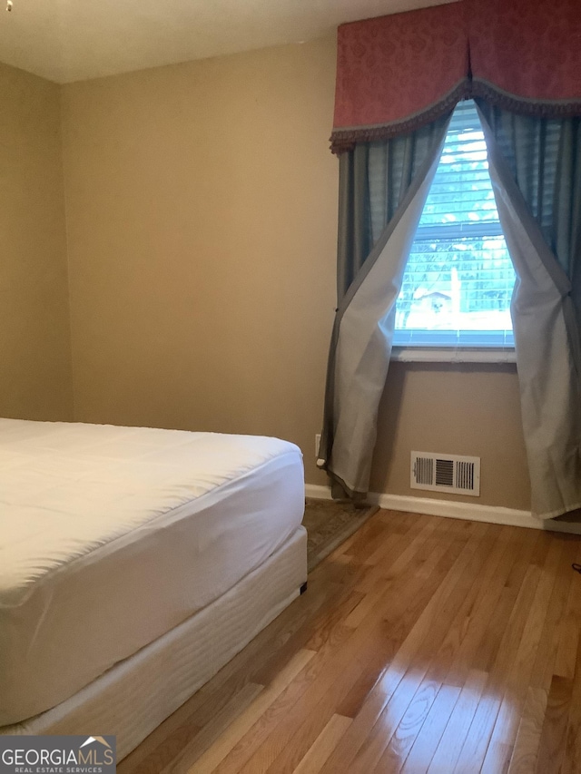 unfurnished bedroom featuring visible vents, baseboards, and wood finished floors