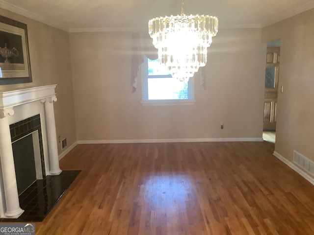 unfurnished living room with wood finished floors, visible vents, a tile fireplace, crown molding, and a chandelier