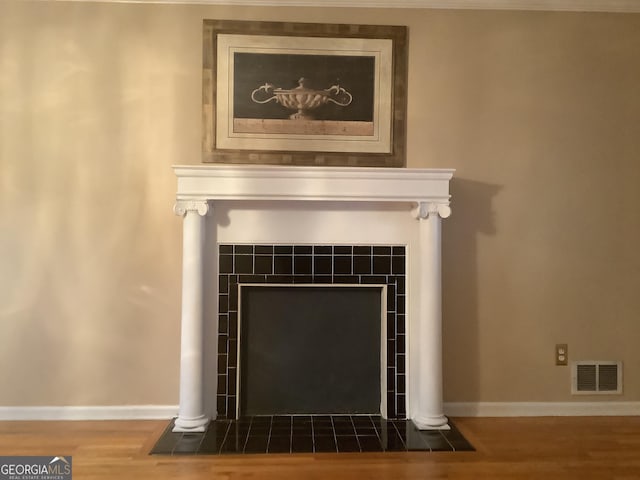 room details featuring wood finished floors, a fireplace, visible vents, and baseboards