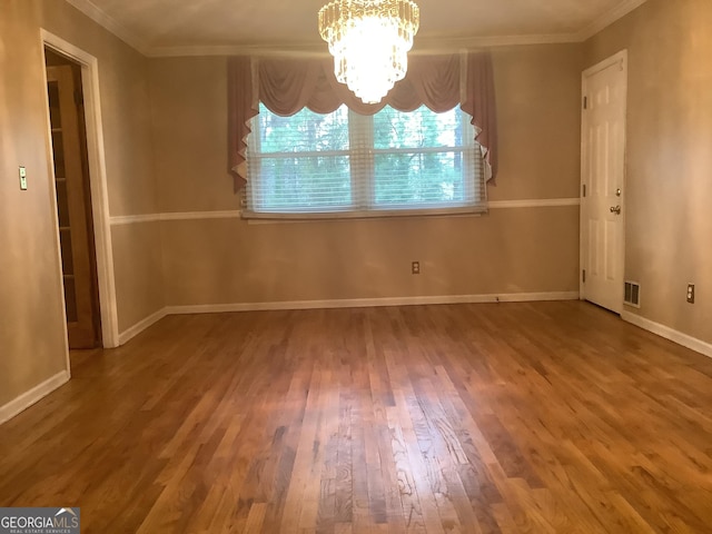 unfurnished dining area with wood finished floors, baseboards, visible vents, ornamental molding, and a chandelier