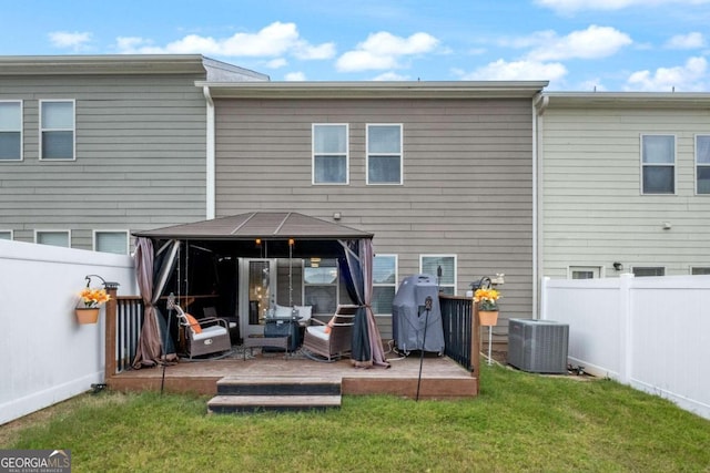 rear view of property with cooling unit, a gazebo, and a lawn