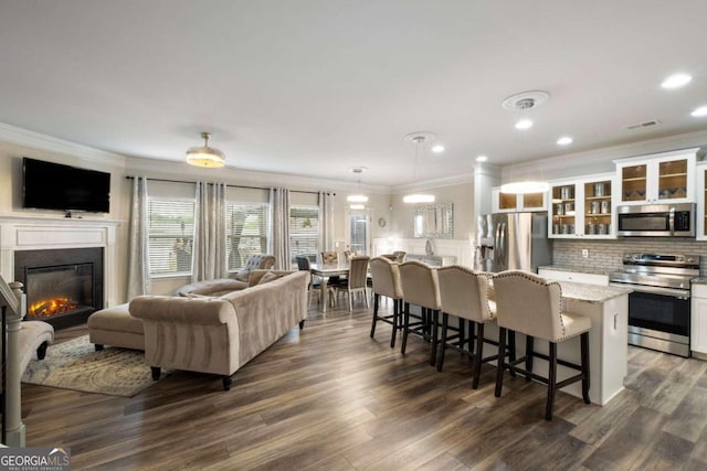 kitchen featuring a kitchen bar, appliances with stainless steel finishes, ornamental molding, and white cabinetry