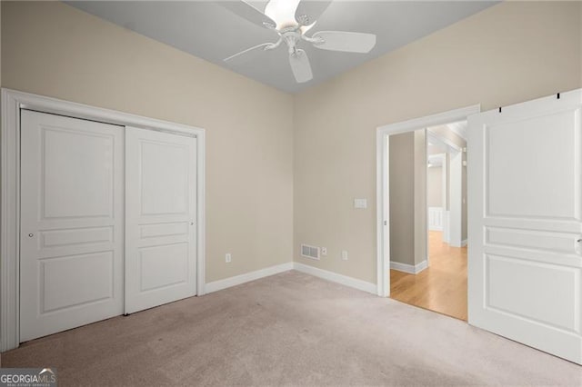 unfurnished bedroom with ceiling fan, light carpet, and a closet