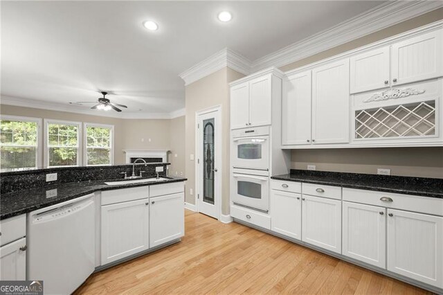 kitchen featuring light hardwood / wood-style floors, dark stone countertops, white cabinets, white appliances, and ceiling fan