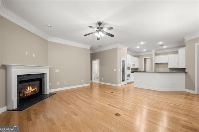 unfurnished living room featuring ceiling fan, a fireplace, crown molding, and light hardwood / wood-style flooring