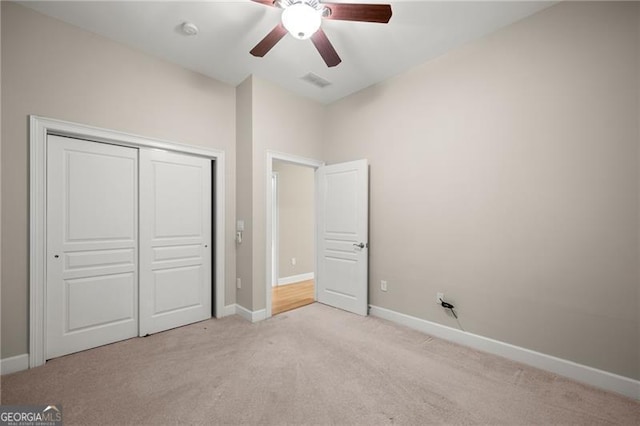 unfurnished bedroom featuring ceiling fan, light colored carpet, and a closet