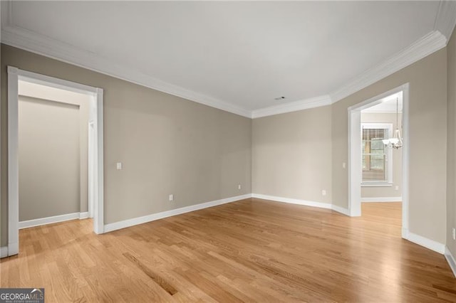 empty room with light wood-type flooring, crown molding, and a chandelier