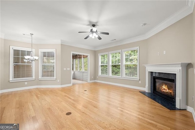 unfurnished living room with ceiling fan with notable chandelier, a fireplace, light hardwood / wood-style floors, and crown molding