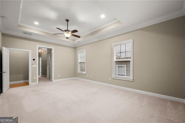 unfurnished bedroom featuring a raised ceiling, crown molding, light carpet, and ceiling fan