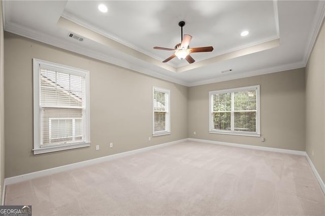 empty room featuring crown molding, a tray ceiling, ceiling fan, and light colored carpet