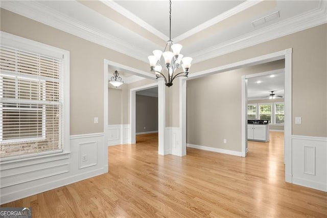 unfurnished dining area with ceiling fan with notable chandelier, light hardwood / wood-style floors, and ornamental molding