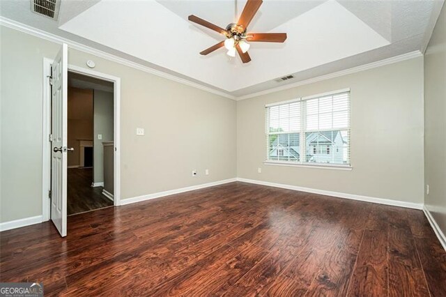 unfurnished room with crown molding, ceiling fan, dark hardwood / wood-style flooring, and a tray ceiling