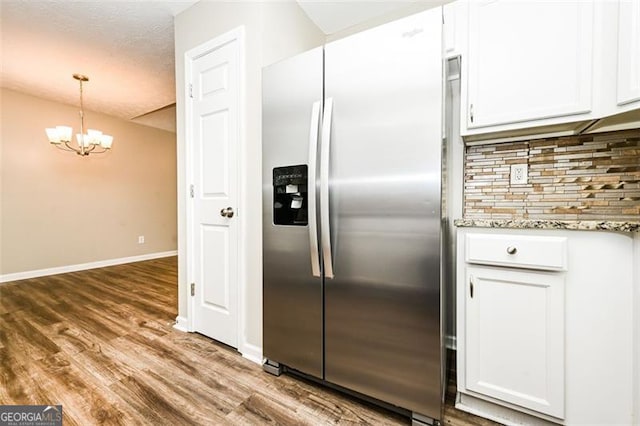 kitchen with pendant lighting, stainless steel refrigerator with ice dispenser, hardwood / wood-style flooring, and white cabinetry