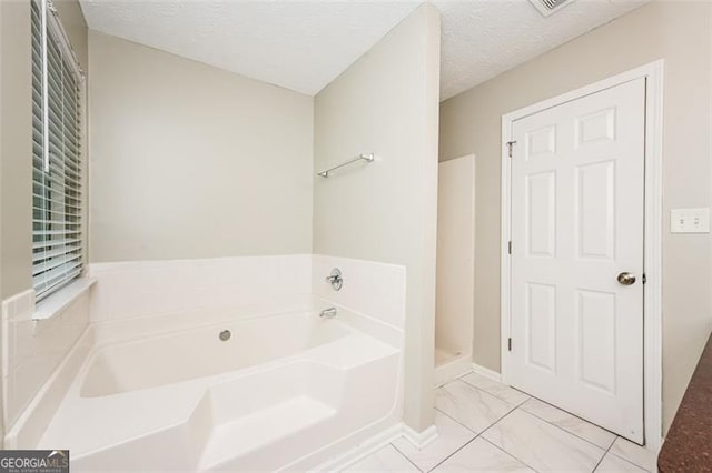 bathroom with a bathing tub and a textured ceiling