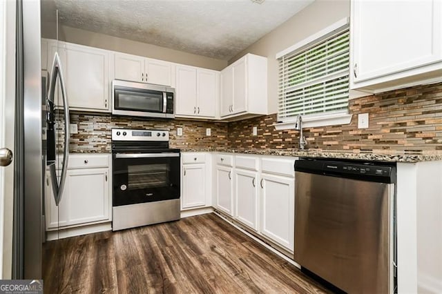 kitchen featuring dark stone countertops, stainless steel appliances, tasteful backsplash, white cabinets, and dark hardwood / wood-style flooring