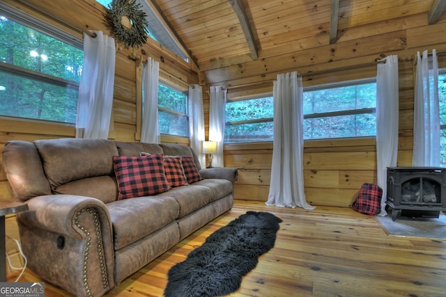 living room with wood ceiling, lofted ceiling with beams, wood walls, a wood stove, and wood-type flooring