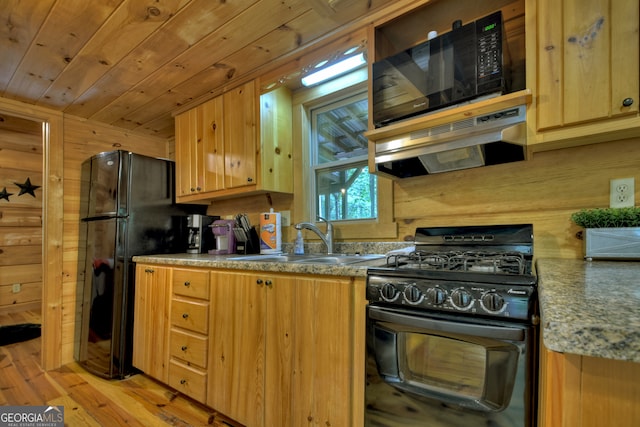 kitchen with light hardwood / wood-style flooring, wooden walls, black appliances, and exhaust hood