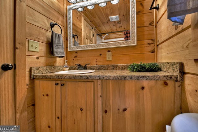 bathroom with wooden ceiling, wood walls, and vanity