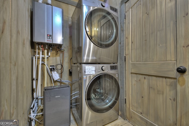 washroom featuring wooden walls, tankless water heater, and stacked washing maching and dryer