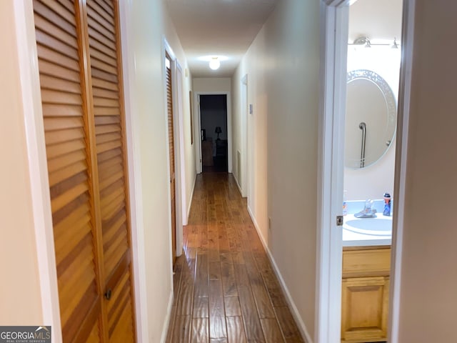 corridor with dark hardwood / wood-style flooring and sink