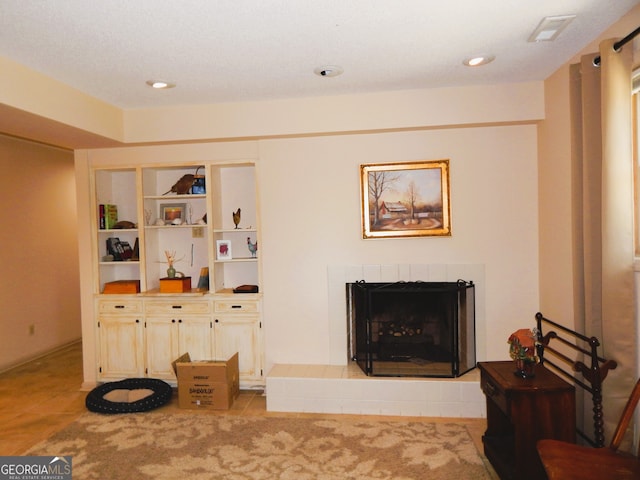 living room featuring a tiled fireplace and light tile patterned floors