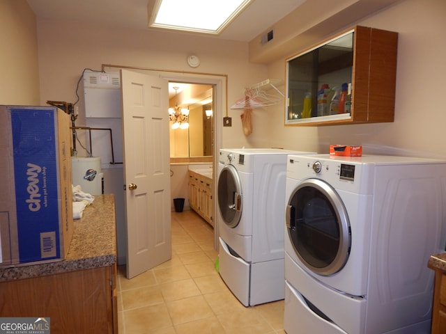 laundry area featuring washing machine and dryer, light tile patterned floors, and cabinets