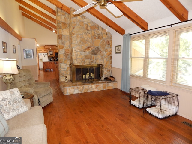 living room with ceiling fan, beam ceiling, high vaulted ceiling, a fireplace, and hardwood / wood-style floors