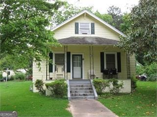 bungalow-style house featuring covered porch and a front yard