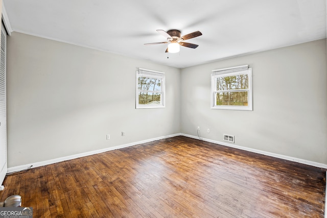 unfurnished room featuring ceiling fan, dark hardwood / wood-style floors, and a healthy amount of sunlight