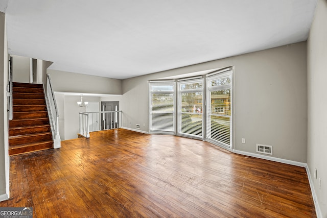 unfurnished living room with a notable chandelier and hardwood / wood-style flooring