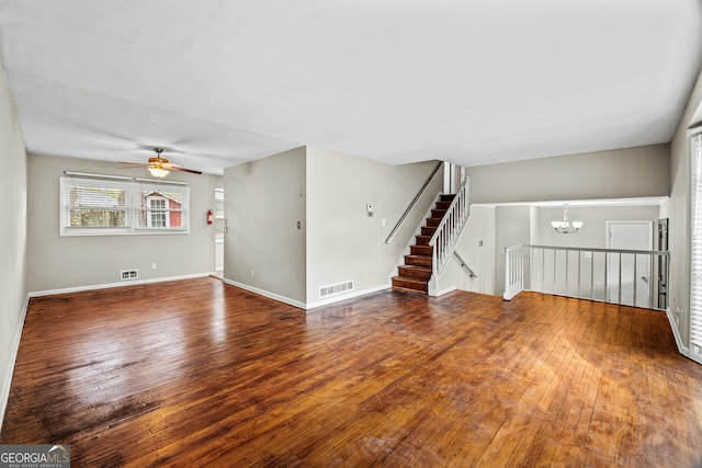 unfurnished living room featuring hardwood / wood-style flooring and ceiling fan with notable chandelier